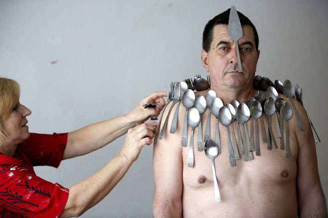 Muhibija Buljubasic, 56, stands as his wife Senija puts cutlery on his body in Srebrenik